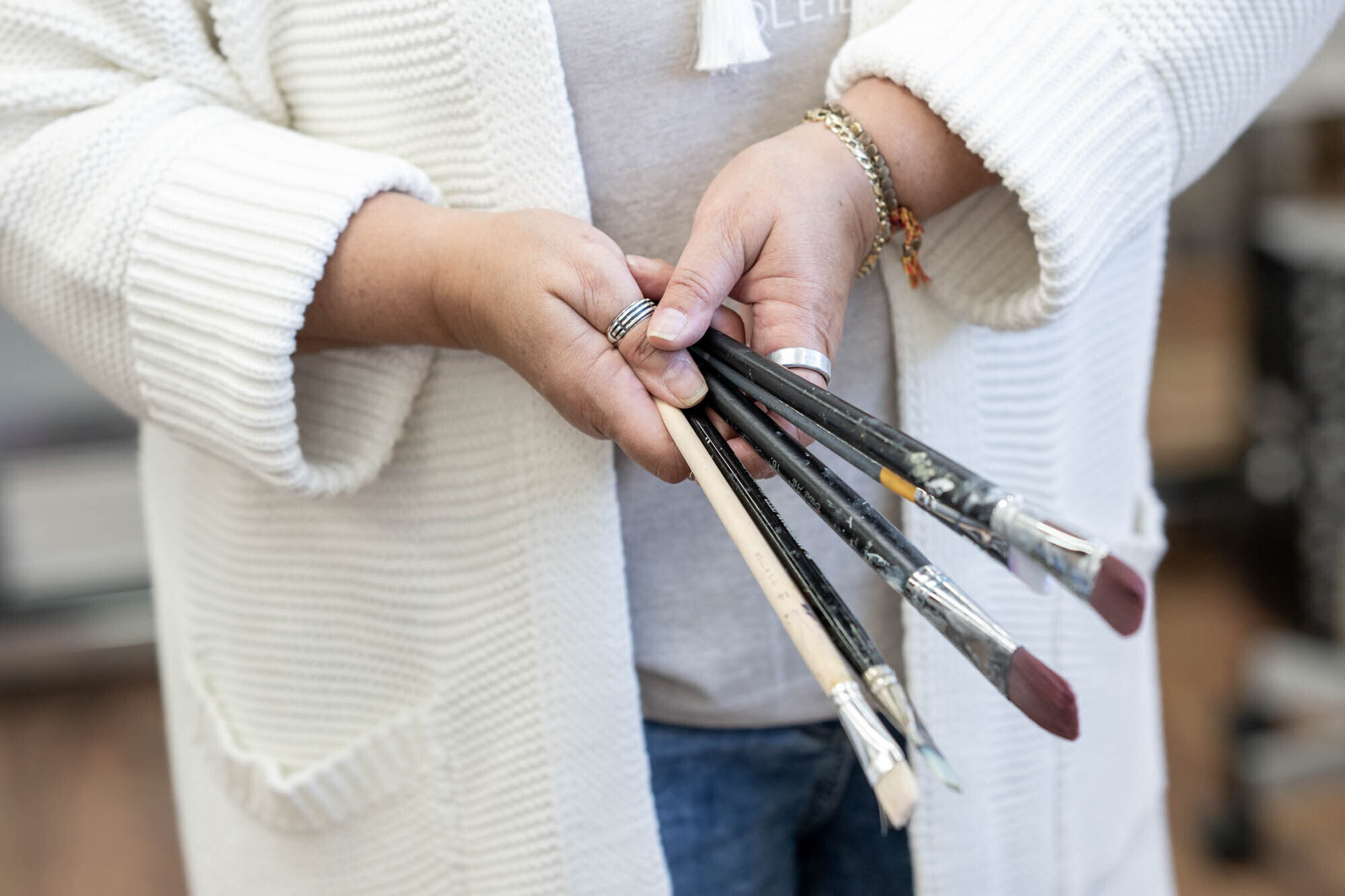 Claudia Lerch hält einen Strauss Pinsel in den Händen im Atelier zum Glück