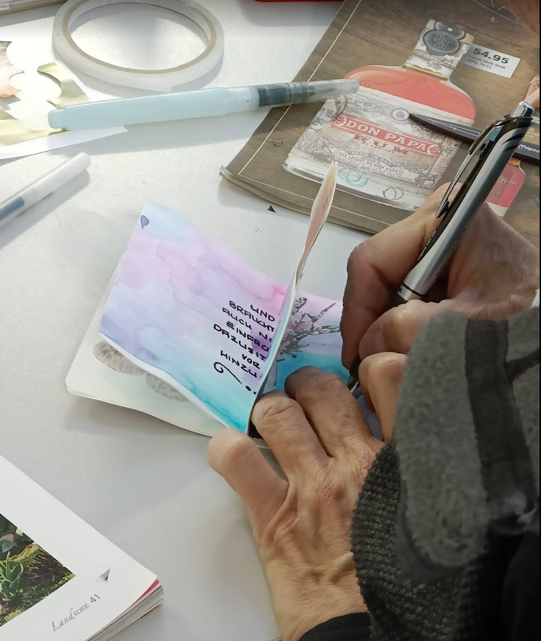 Kursteilnehmerin arbeitet an einem Glücksbüchlein